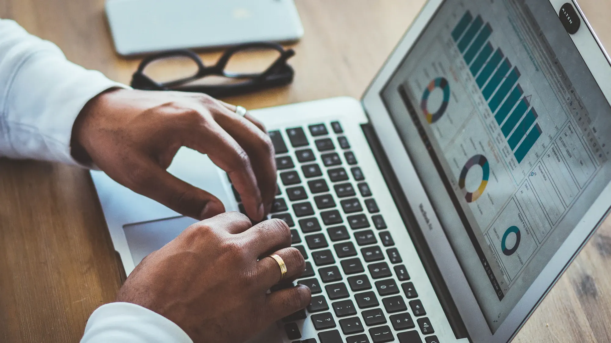 Hands typing on a laptop showing financial charts