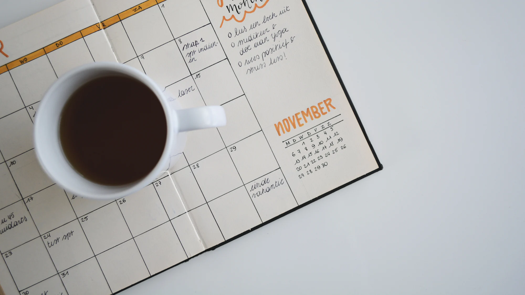 A cup of coffee on an open monthly planner