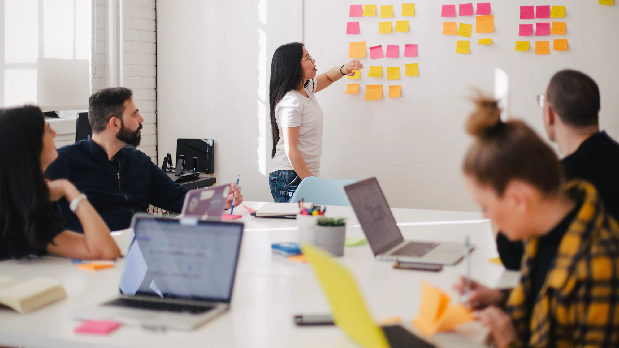 A team standing at a whiteboard covered in coloured sticky notes