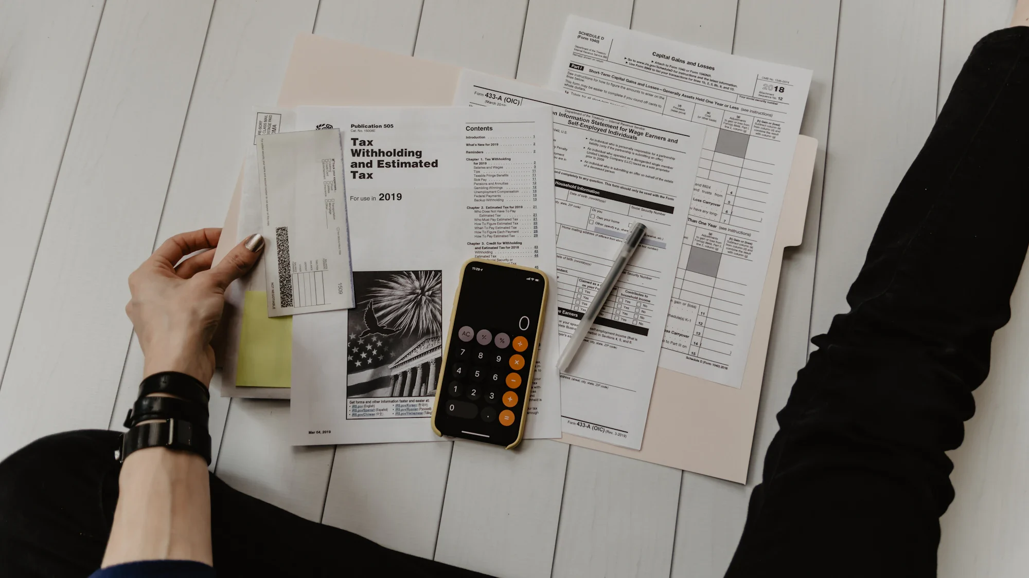 Printed tax documents and a calculator on a white desk