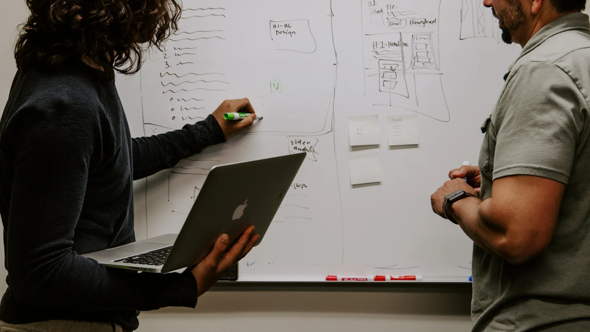 Two colleagues discussing sketches at a whiteboard