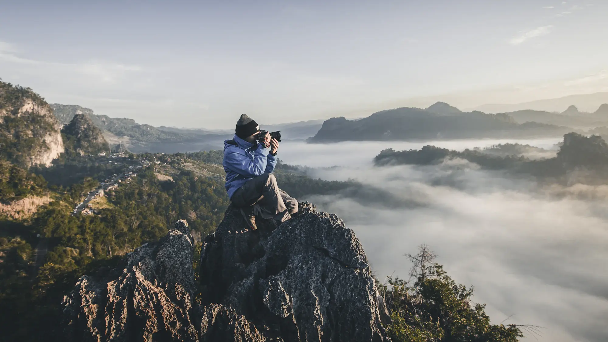 A photographer with a camera standing above a valley at sunrise