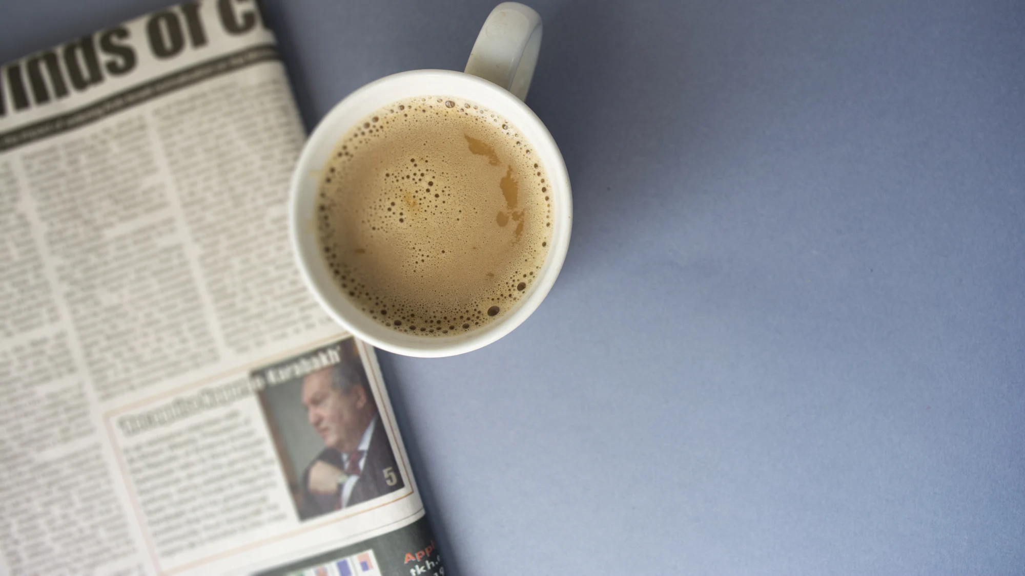 A folded newspaper beside a cup of coffee