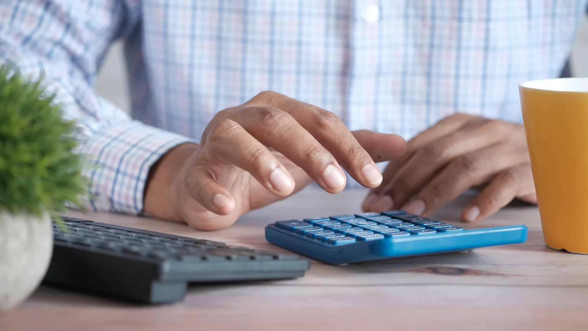 Hands using a calculator next to a keyboard