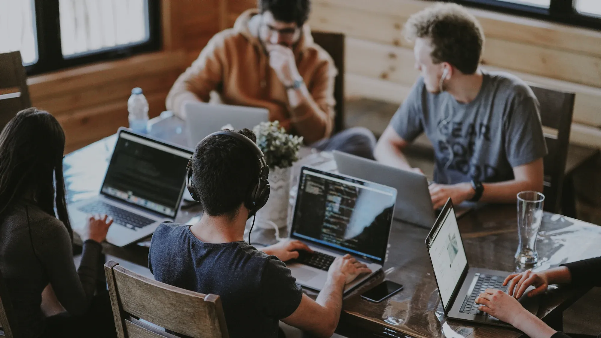 A team working on laptops around a shared table in a co-working space