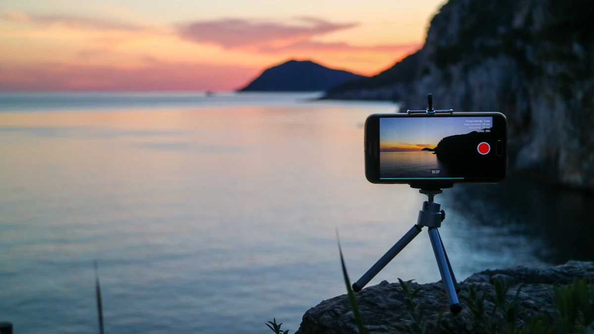A smartphone on a small tripod filming a sunset over the sea