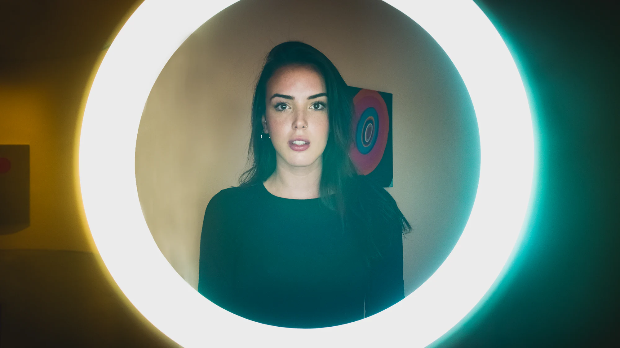 A woman framed by the glow of a ring light