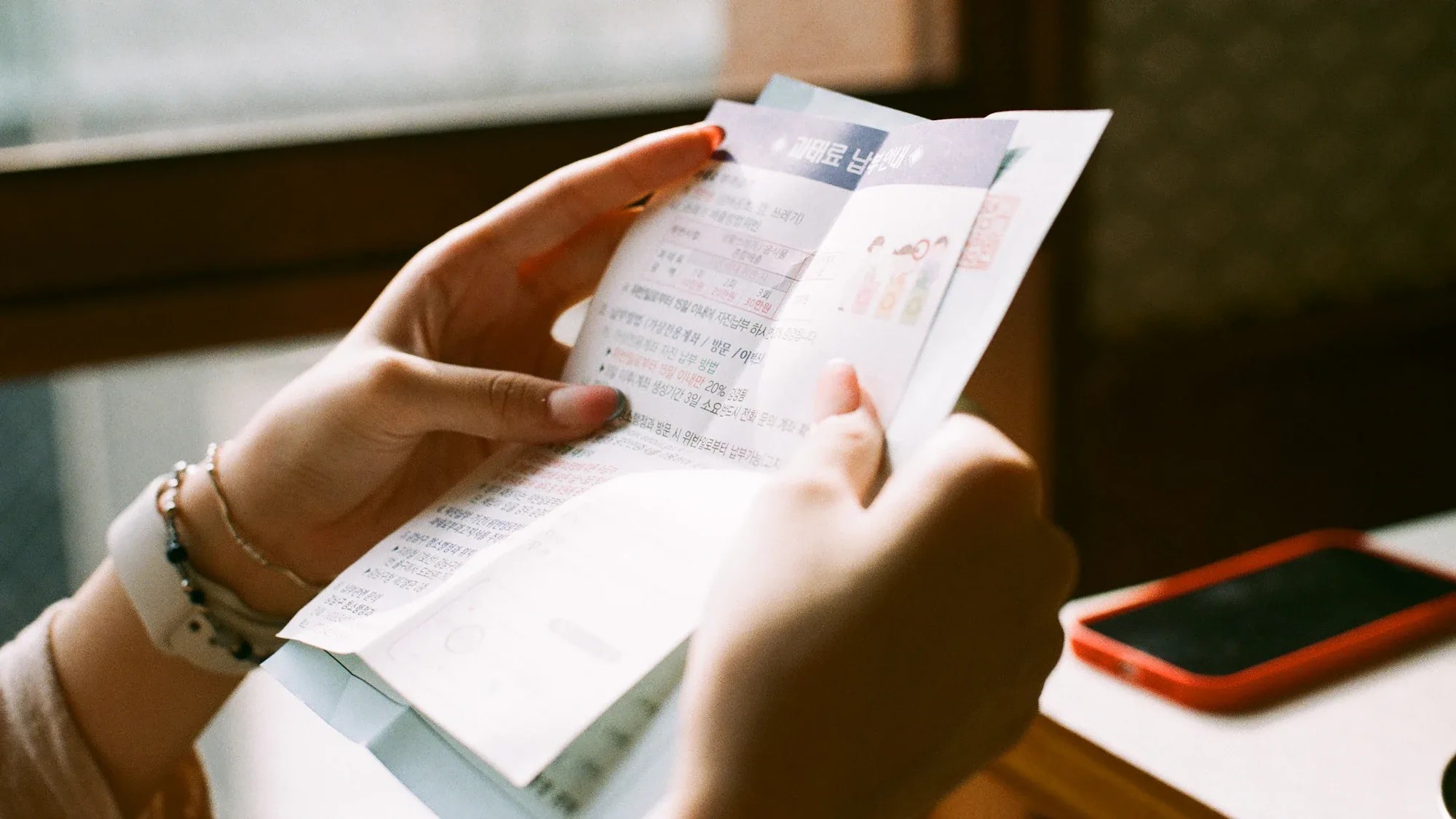Hands holding a printed receipt beside a phone